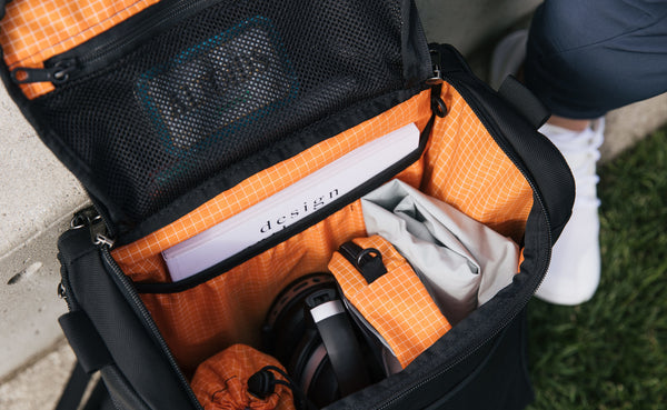 The interior of the Cambiata with a book, headphones, a rain shell, a stuff sack, and a 3D Organizer Cube inside.